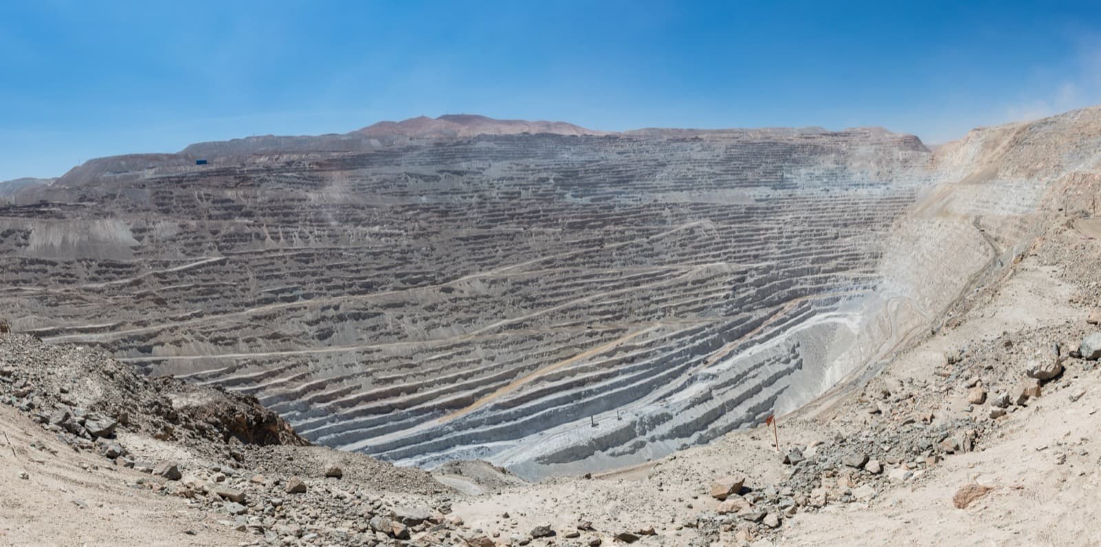 Aerial view of an open-pit mine with a loader and conveyor